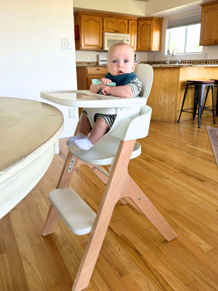 Cute baby boy sitting in the Mockingbird high chair at the table.