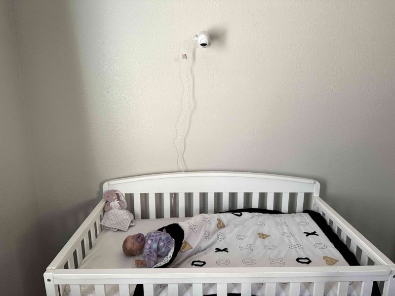 Momcozy Video Baby Monitor installed on wall, baby in crib